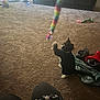 animal, black_and_white_cat, blanket, cables, carpet, cat, colorful_toy, entertainment_unit, floor, furniture, home, indoor, living_room, patterned_clothing, person, pet, playful, seated, shoes, toy