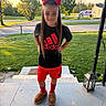 child, girl, red_bow, adidas, shorts, shirt, slippers, socks, porch, steps, grass, trees, sunset, smile, outdoor, street, house, lantern, person, casual