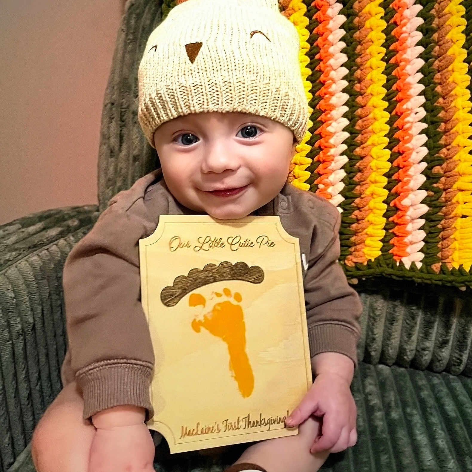 Maclaine is registered to the contest to win money with this photo: baby, blanket, child, couch, cozy, crocheted_blanket, cute, face, footprint, hand, hat, holiday, indoors, infant, knitted_hat, plaque, portrait, sitting, smile, thanksgiving