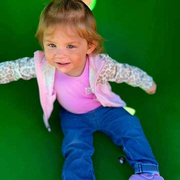 Raylee is registered to the contest to win money with this photo: toddler, child, slide, playground, outdoor, smiling, pink_shirt, jacket, blue_pants, purple_shoes, happy, casual_clothing, fun, active, young_child, leisure, daylight, cute, portrait, play