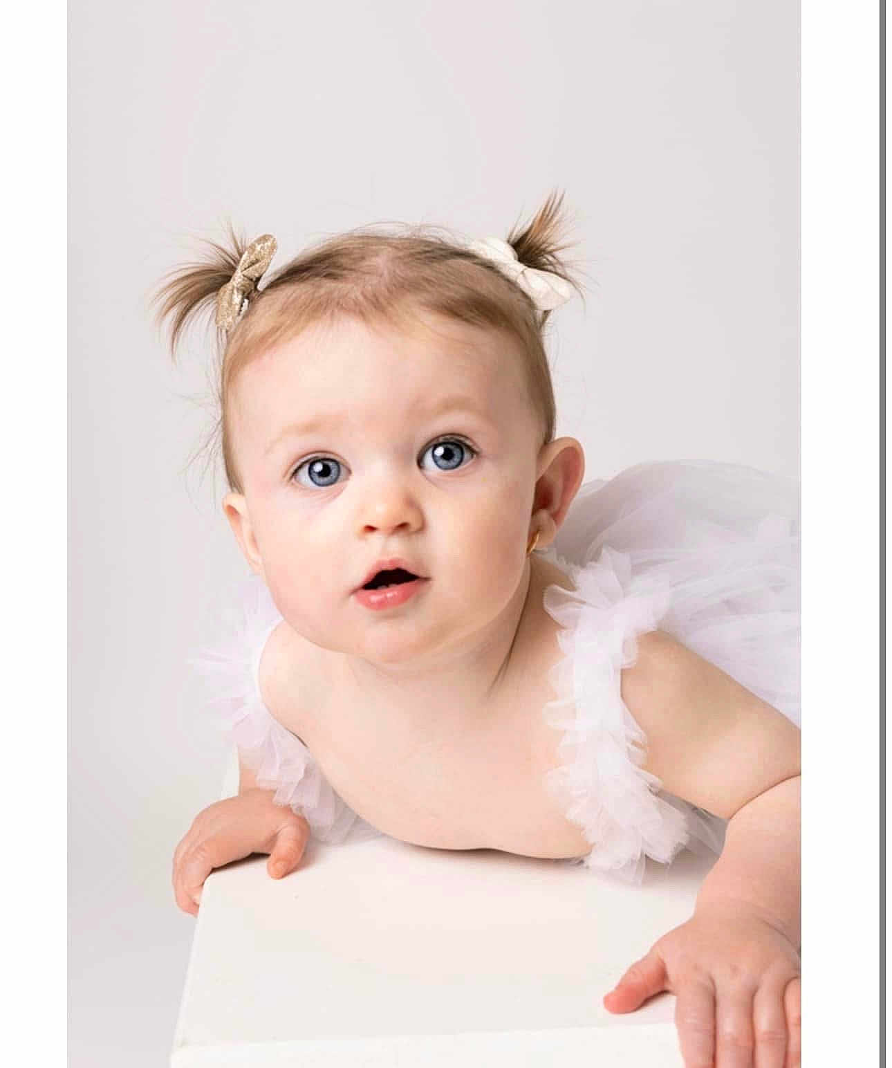 Aria joined the competition — help win amazing prizes! baby, child, tutu, pigtails, bows, blue_eyes, cute, infant, portrait, white_background, curious, soft_lighting, studio_photo, small_hands, face, expression, innocence, adorable, closeup, clothing