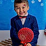 child, boy, smile, face_paint, suit, bow_tie, lollipop, red, white, blue_background, snowflakes, indoor, portrait, happy, sitting, wooden_bench, festive, holiday, cute, young