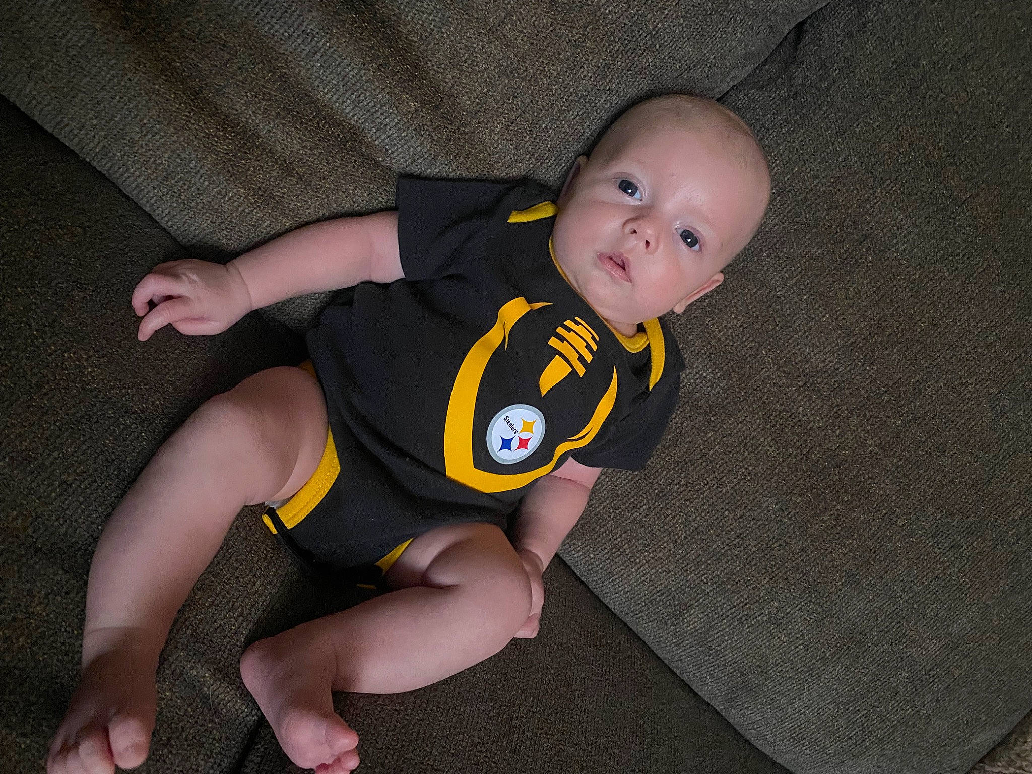 Jiraiya is registered to the contest to win money with this photo: baby, baby_products, baby_toddler_clothing, cheek, child, comfort, finger, flooring, foot, fun, human_leg, knee, leg, person, personal_protective_equipment, sitting, sleeve, sock, t_shirt, thigh