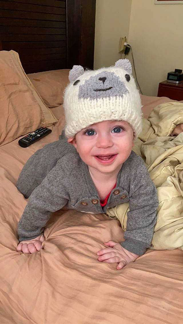 Sly is registered to the contest to win money with this photo: baby, baby_toddler_clothing, cap, cheek, child, comfort, eye, face, flooring, happy, head, headwear, joy, knit_cap, mammal, nose, outerwear, person, skin, sleeve