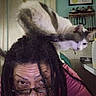 Missykitty is registered to the contest to win money with this photo: cat, person, dreadlocks, glasses, indoor, kitchen, wall_art, jewelry, shelf, playful, curious, feline, head, portrait, home, decor, casual, funny, black_hair, white_cat