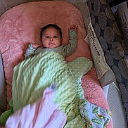Arielle is registered to the contest to win money with this photo: baby, blanket, playpen, infant, pink, green, face, hand, clothing, soft, cushion, sleeping_area, cozy, indoor, child, fabric, textile, cute, newborn, resting