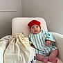 baby, blanket, bodypart, bonnet, cap, chair, clothing, couch, cushion, face, finger, furniture, hat, head, homedecor, newborn, person, photography, portrait, sitting