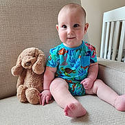 Grayson joined the competition — help win amazing prizes! baby, child, plush_toy, stuffed_animal, couch, sofa, onesie, blue_clothing, smile, sitting, indoor, furniture, crib, baby_boy, cute, soft_toy, hand_holding, foot, face, room