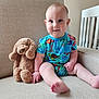 baby, child, plush_toy, stuffed_animal, couch, sofa, onesie, blue_clothing, smile, sitting, indoor, furniture, crib, baby_boy, cute, soft_toy, hand_holding, foot, face, room