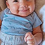 baby, smiling, blue_shirt, shorts, sharks, towel, cushion, cheeks, face, eyes, skin, clothing, infant, person, cute, hand, lying_down, indoors, soft_texture, happy