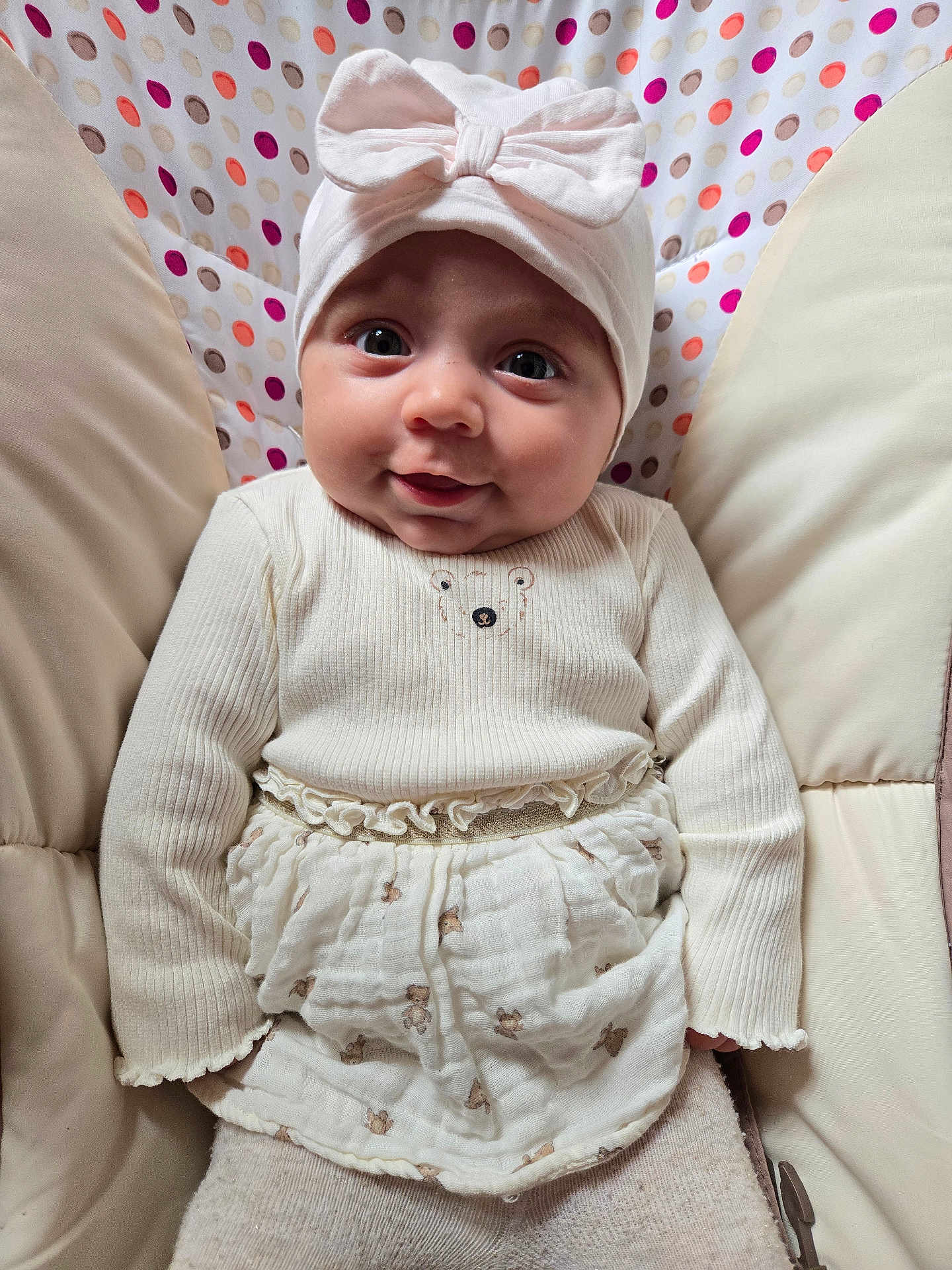 Maïa a rejoint le concours — aidez-le/la à gagner de superbes lots ! baby, child, smiling, hat, bow, white_clothing, cushion, polka_dot, pattern, sitting, portrait, cute, infant, happy, indoors, fabric, soft, person, closeup, face