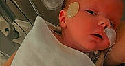Ayden is registered to the contest to win money with this photo: newborn, baby, infant, child, portrait, sleepy, face, hospital, blanket, medical, sticker, tubing, swaddled, close_up, head, eyes, nose, mouth, caregiver, indoor