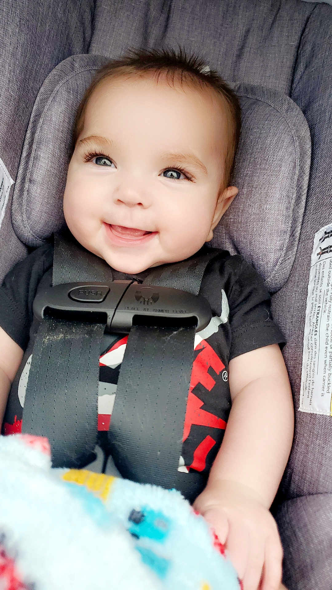 Weston is registered to the contest to win money with this photo: baby, smiling, car_seat, child, infant, straps, blanket, black_shirt, happy, cute, face, person, seatbelt, portrait, closeup, blue_eyes, hair, sitting, indoors, child_safety