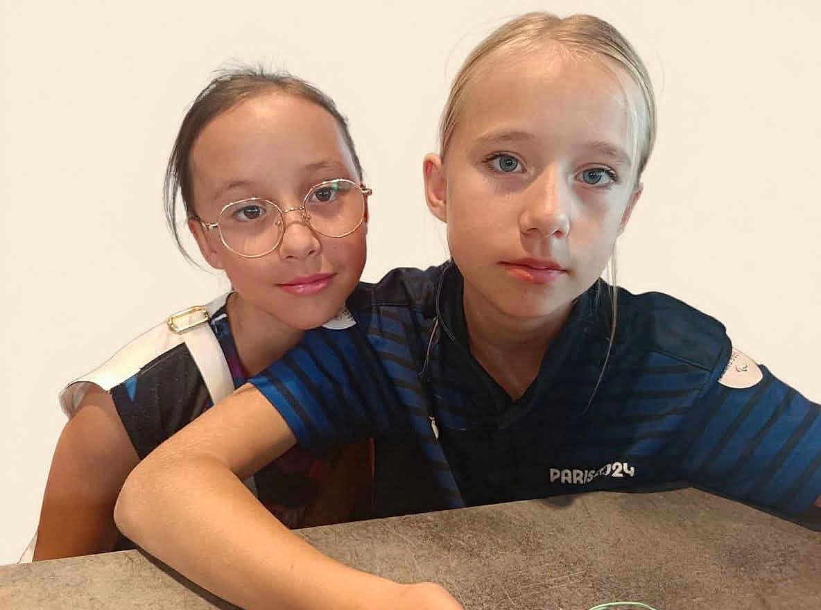 Fiona Lea a rejoint le concours — aidez-le/la à gagner de superbes lots ! child, children, girl, glasses, blue_shirt, portrait, table, indoor, casual, face, young, person, sitting, serious, smile, light_background, shoulder, hair, expression, friendship