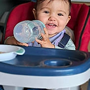 Bryan participe au concours pour gagner de l'argent avec cette photo : toddler, child, high_chair, smiling, sippy_cup, cheerful, indoor, baby, feeding, cute, happy, face, clothing, seat, kitchen, portrait, young_child, table, bottle, cheeks