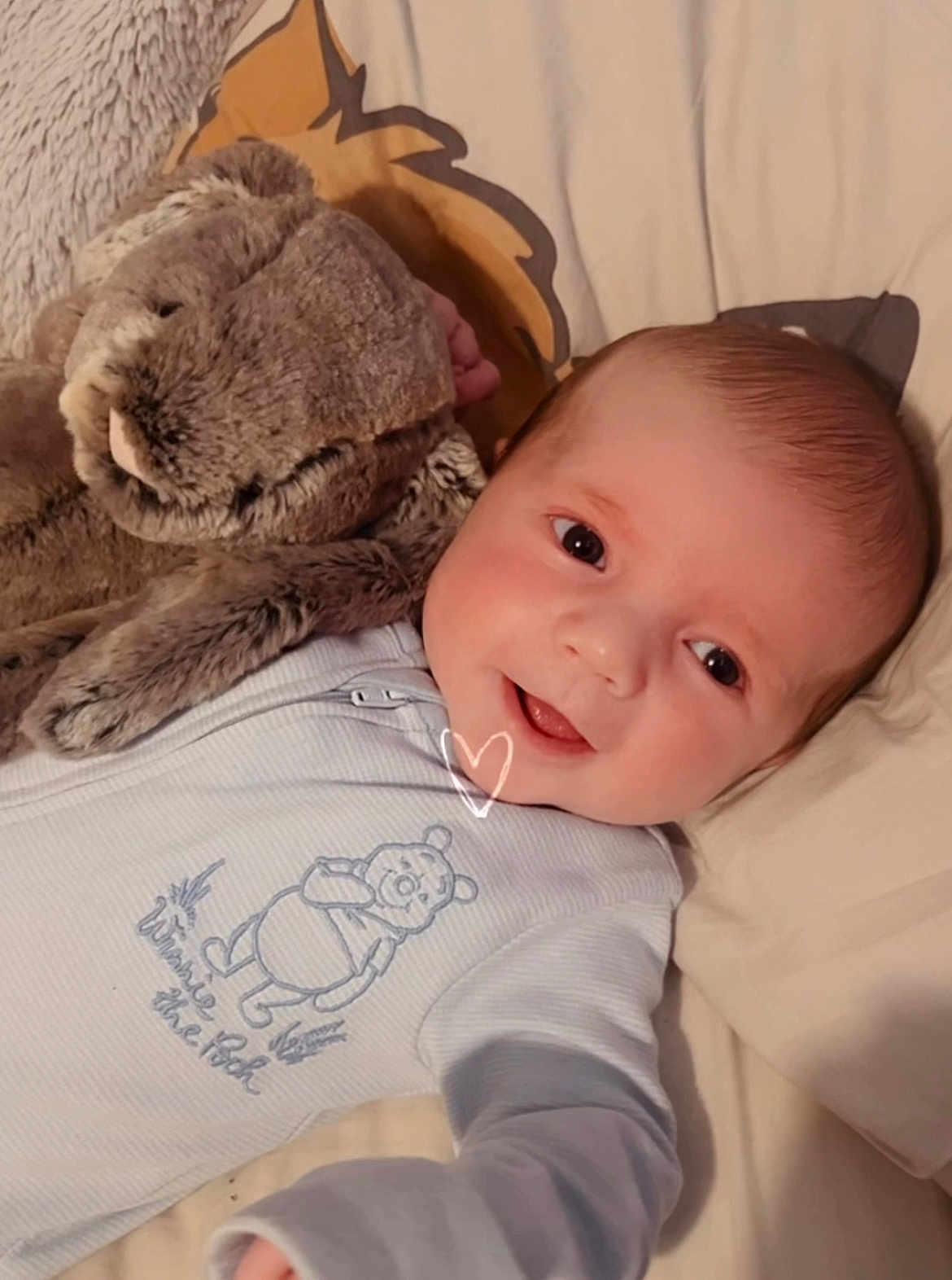 Theo joined the competition — help win amazing prizes! baby, infant, smile, face, onesie, stuffed_animal, plush_toy, bed, pillow, cuddling, cute, winnie_the_pooh, soft_toy, child, happy, lying_down, cozy, indoor, portrait, toddler