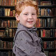 Henry is registered to the contest to win money with this photo: child, boy, red_hair, smile, shirt, dinosaur_print, suspenders, library, bookshelf, books, portrait, indoors, cute, happy, freckles, face, young, fashion, background, knowledge