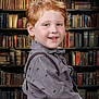 child, boy, red_hair, smile, shirt, dinosaur_print, suspenders, library, bookshelf, books, portrait, indoors, cute, happy, freckles, face, young, fashion, background, knowledge