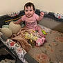 Elodie joined the competition — help win amazing prizes! baby, playpen, blanket, stuffed_toy, pink_clothing, tongue_out, smiling, indoor, child, cute, floral_pattern, toy, sitting, face, person, infant, happy, cozy, soft_toy, head