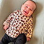 Ellie a rejoint le concours — aidez-le/la à gagner de superbes lots ! baby, smiling, infant, leopard_print, clothing, lying_down, cute, happy, face, child, person, black_pants, sleeves, hand, skin, indoors, texture, fabric, portrait, warm_lighting