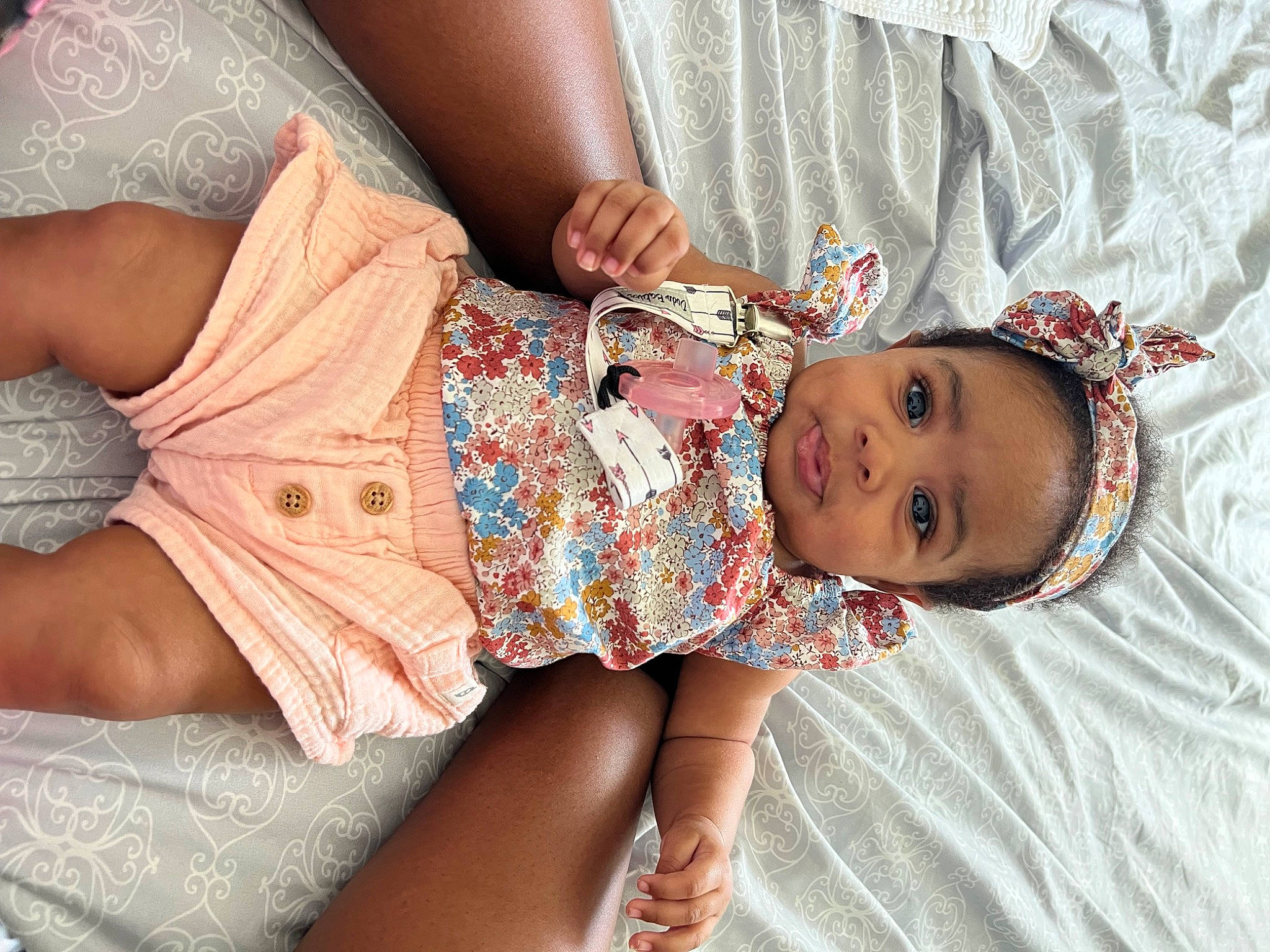 Nylah is registered to the contest to win money with this photo: arm, baby, baby_products, baby_toddler_clothing, cheek, comfort, dress, finger, glasses, hand, human, human_body, mouth, pattern, person, pink, skin, sleeve, textile, thigh