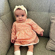 Kaïly a rejoint le concours — aidez-le/la à gagner de superbes lots ! baby, child, infant, girl, headband, bow, dress, orange, checkered, socks, shoes, couch, gray, furniture, indoors, smile, portrait, sitting, cute, person