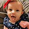 baby, child, face, headband, red_bow, tongue_out, blue_dress, stars_pattern, blanket, cozy, happy, smiling, infant, cute, portrait, indoors, hand, expression, clothing, person