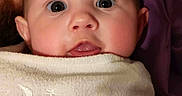 Noah is registered to the contest to win money with this photo: baby, closeup, face, blanket, embroidery, moon, stars, wide_eyes, curious, soft_texture, infant, child, wrapped, snug, portrait, indoors, human, head, skin, cute