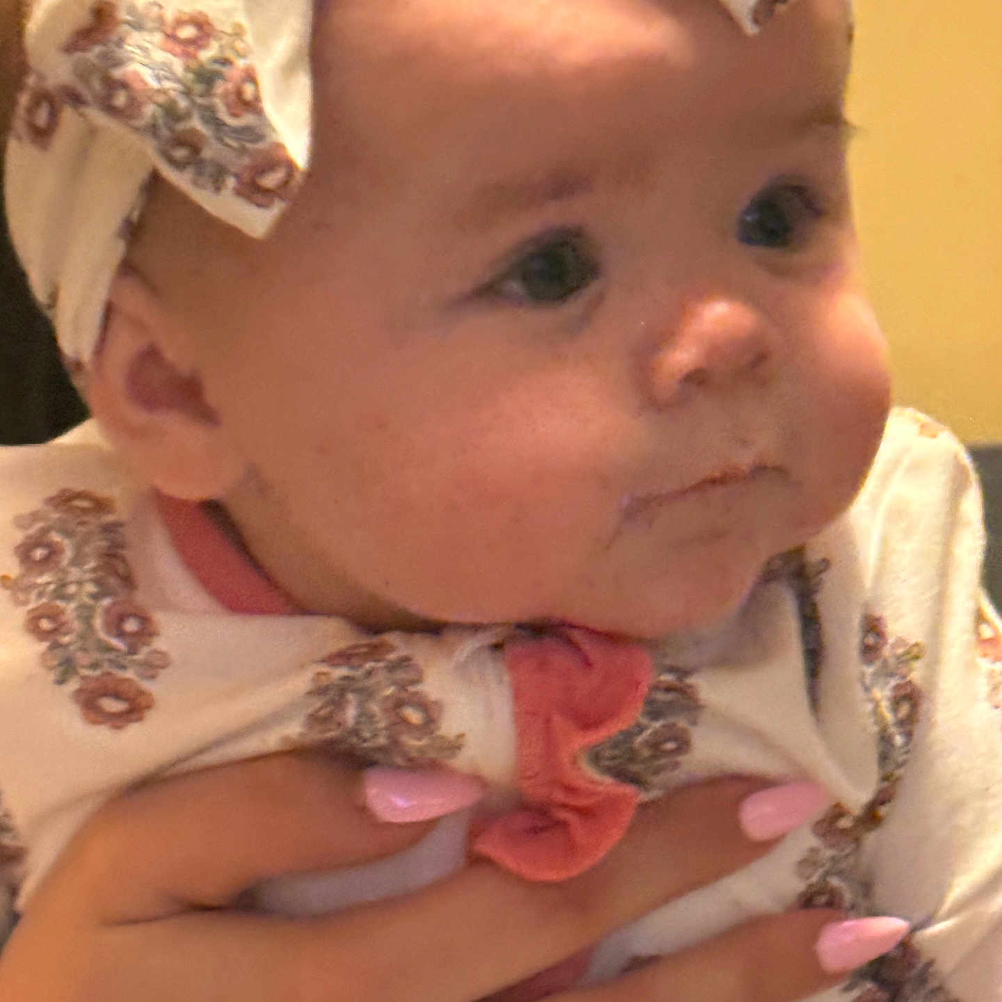 Mattie-Jean is registered to the contest to win money with this photo: baby, bow, cheeks, chubby_cheeks, close_up, cute, eyes, fabric, gaze, hand, headband, holding, indoor, infant, onesie, patterned_clothing, person, pink_nails, portrait, soft_lighting