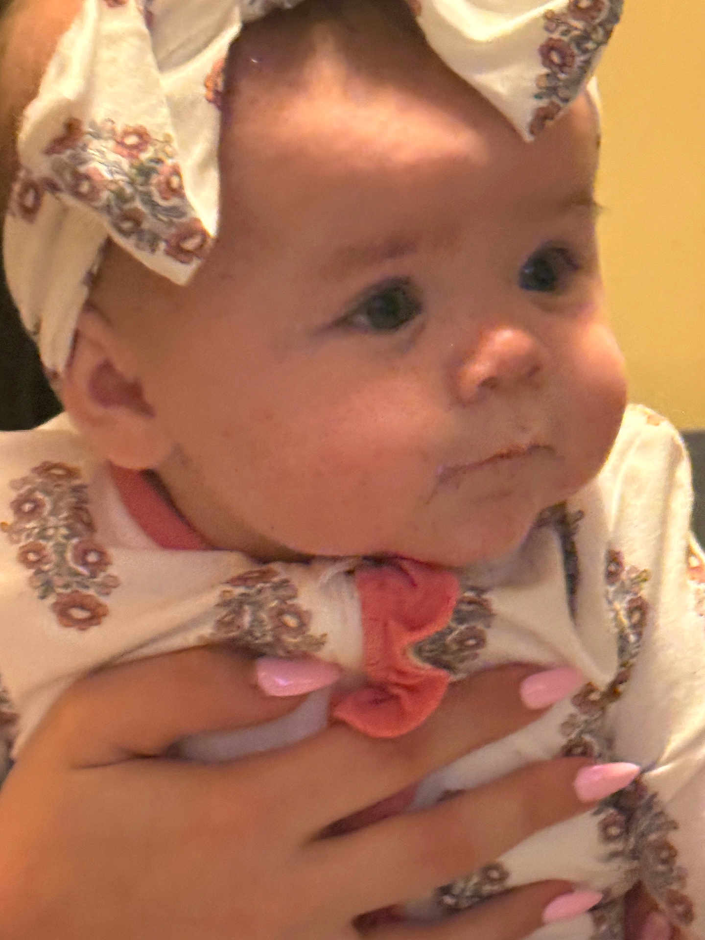 Mattie-Jean is registered to the contest to win money with this photo: baby, bow, cheeks, chubby_cheeks, close_up, cute, eyes, fabric, gaze, hand, headband, holding, indoor, infant, onesie, patterned_clothing, person, pink_nails, portrait, soft_lighting