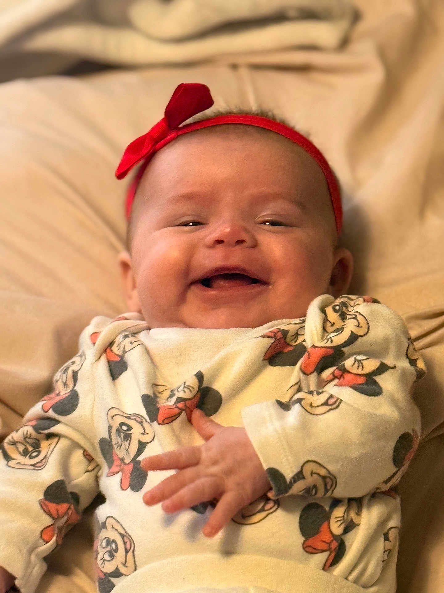Mattie-Jean is registered to the contest to win money with this photo: baby, infant, smiling, red_headband, bow, mickey_mouse, pattern, clothing, lying_down, soft_surface, cute, happy, child, person, face, hand, apparel, indoors, portrait, cozy