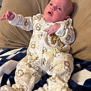 Kallie is registered to the contest to win money with this photo: baby, infant, onesie, animal_print, pillow, blanket, blue, white, beige, indoor, person, child, cute, sleepwear, newborn, resting, portrait, young, soft, cozy