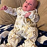 baby, infant, onesie, animal_print, pillow, blanket, blue, white, beige, indoor, person, child, cute, sleepwear, newborn, resting, portrait, young, soft, cozy