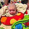 Kallie joined the competition — help win amazing prizes! baby, infant, child, towel, activity_center, toy, colorful, red, orange, green, blue, person, hands, support, indoor, closeup, face, head, expression, seated