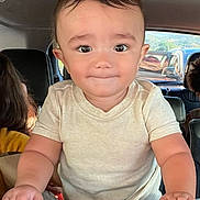 Gianni is registered to the contest to win money with this photo: toddler, child, car_interior, seat, hands, curious, portrait, person, vehicle, window, face, young_child, casual_clothing, short_sleeves, baby, grip, car_seat, looking_at_camera, smile, inside_car
