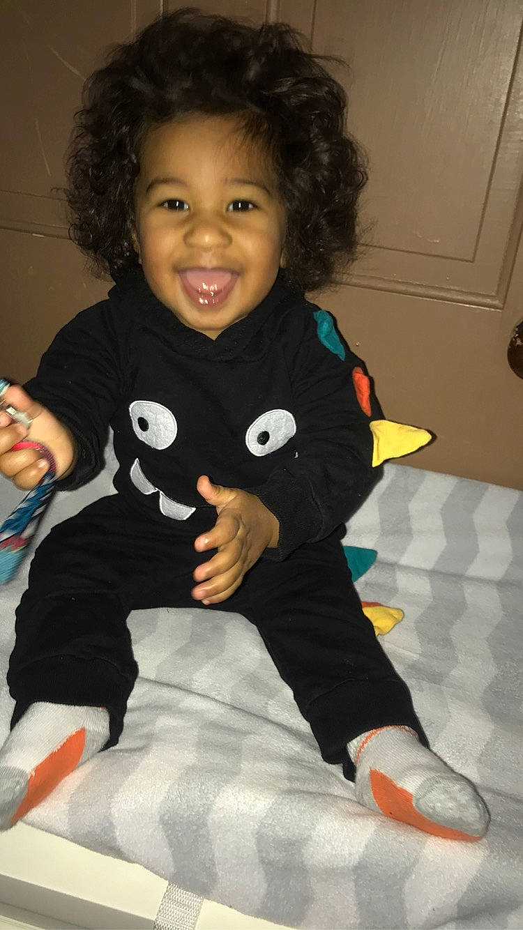 Camryn is registered to the contest to win money with this photo: arm, baby, baby_toddler_clothing, cheek, eye, finger, gesture, hair, hairstyle, hand, happy, head, human_body, joy, person, skin, sleeve, smile, sock, t_shirt