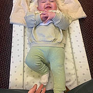 Harper joined the competition — help win amazing prizes! baby, child, infant, smiling, lying_down, changing_pad, blanket, hand, carpet, clothing, sock, green_pants, happy, indoor, person, cute, cozy, star_pattern, fabric, soft