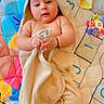 baby, towel, hood, bear_ears, play_mat, toy, blanket, infant, child, cute, soft_toy, colorful, lying_down, indoors, skin, smiling, hands, feet, face, person