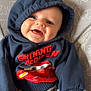 baby, smiling, hoodie, navy_blue, lightning_mcqueen, red, blue_blanket, beaded_pacifier, elephant_pattern, infant, cute, clothing, child, hand, face, happy, indoors, person, young_child, sitting