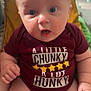 baby, infant, child, onesie, maroon_clothing, chubby, sitting, indoor, face, wide_eyes, expression, hand, legs, pillow, blurred_background, home, cute, person, close_up, casual