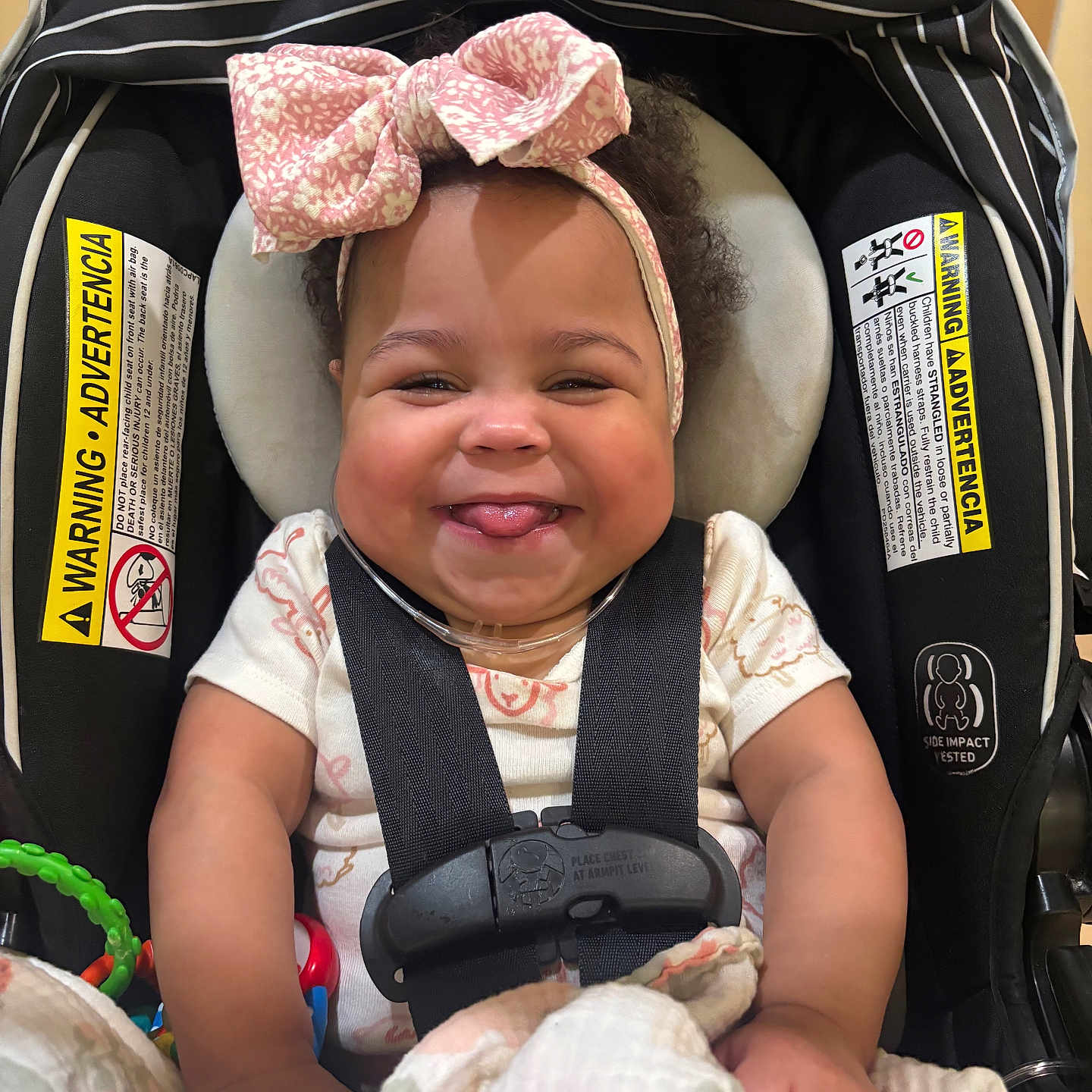 Arianna Long joined the competition — help win amazing prizes! baby, car_seat, headband, pink_bow, smiling, tongue_out, blanket, toy, infant, straps, cute, happy, indoor, child, person, clothing, seat, face, safe, comfort