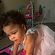 Arianna Long joined the competition — help win amazing prizes! toddler, child, baby, dress, pink, curly_hair, indoors, carpet, toy, quilt, colorful, crawling, person, young_child, cute, exploration, home, soft_lighting, portrait, playtime