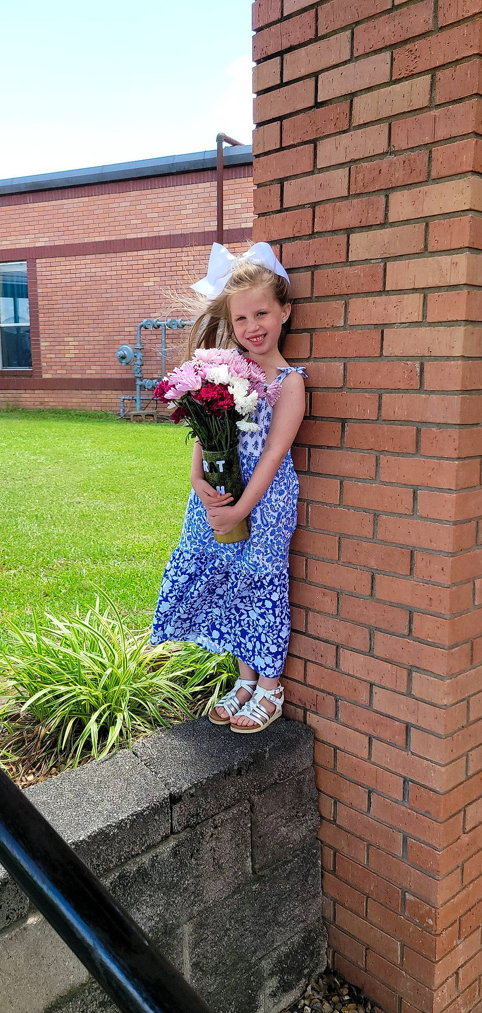 Nevaeh is registered to the contest to win money with this photo: brick, brickwork, day_dress, dress, electric_blue, floral_design, flower, flower_arranging, fun, grass, happy, hat, human_leg, joy, person, plant, shrub, smile, street_fashion, toddler