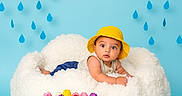 Rayan is registered to the contest to win money with this photo: baby, yellow_hat, fluffy_cushion, clouds, raindrops, blue_background, yellow_rain_boots, tulips, colorful_flowers, indoor, child, cute, spring_theme, playful, portrait, smiling, decor, flower_arrangement, childrens_photography, studio_shot