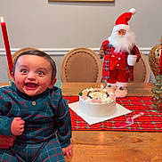 Rayan is registered to the contest to win money with this photo: baby, child, infant, smiling, birthday, cake, santa, christmas, festive, table, tartan, candle, peacock, painting, indoor, portrait, seated, plaid, wooden_furniture, celebration