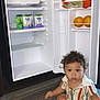 Zakar joined the competition — help win amazing prizes! toddler, child, baby, carpet, striped_shirt, diaper, mini_fridge, open_fridge, food_pouches, oranges, kitchen, curly_hair, indoor, floor, cabinet, expression, sitting, person, curiosity, home