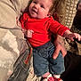 Arizona is registered to the contest to win money with this photo: baby, infant, smiling, red_shirt, denim_shorts, striped_socks, santa_socks, pillow, couch, tattooed_hand, holding, cheeks, cute, portrait, indoor, cozy, blanket, family, happy, closeup