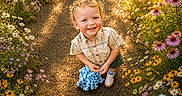 Joel is registered to the contest to win money with this photo: blue_eyes, casual_clothing, child, curly_hair, daisies, garden_path, happy, nature, outdoor, plush_toy, portrait, purple_flowers, shorts, smiling, sneakers, summer, sunlight, toddler, wildflowers, yellow_flowers