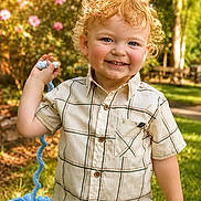 Joel joined the competition — help win amazing prizes! blue_eyes, boy, casual_clothing, child, curly_hair, cute, flowers, garden, grass, greenery, happy, knitted_toy, nature, outdoor, plaid_shirt, portrait, smiling, sunlight, toddler, toy