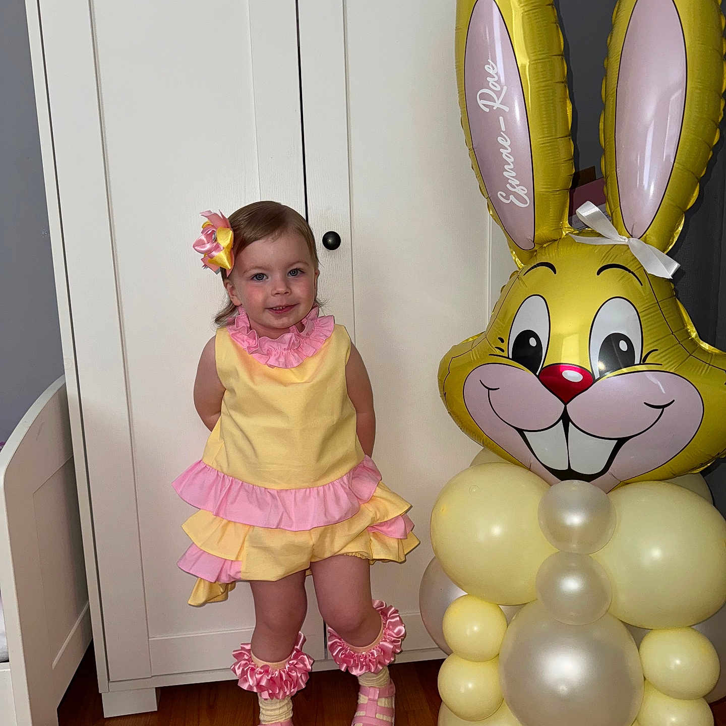 Esmae-Rae joined the competition — help win amazing prizes! balloon_bunny, balloons, bow, cabinet, child, cute_pose, footwear, happy, home, indoor, leg_warmers, party_decoration, person, pink_ruffles, pink_shoes, ribbons, smile, toddler, wooden_floor, yellow_dress